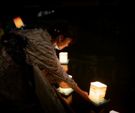 japanese woman putting lamp on river during toro nagashi festival